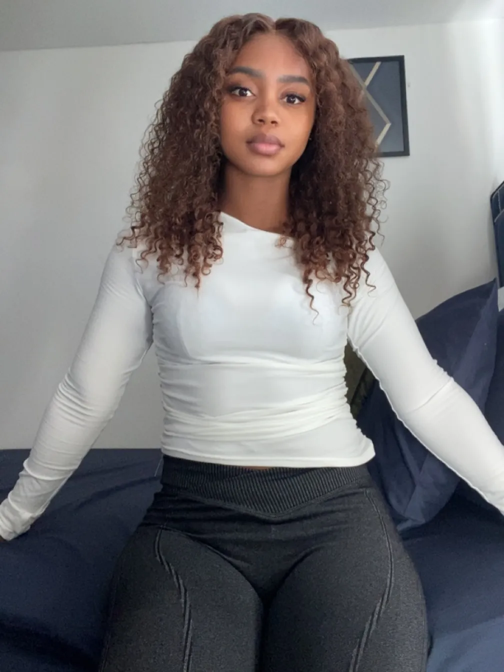 Chloe, Deep Tissue Therapist, white top seated arms on bed portrait at All Queens Wellness Spa, Kindaruma Road, Kilimani, Nairobi.